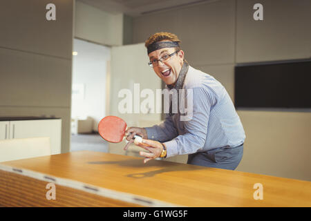 Porträt von begeisterten Geschäftsmann spielen Ping-Pong mit binden umwickelt Kopf im Konferenzraum Stockfoto