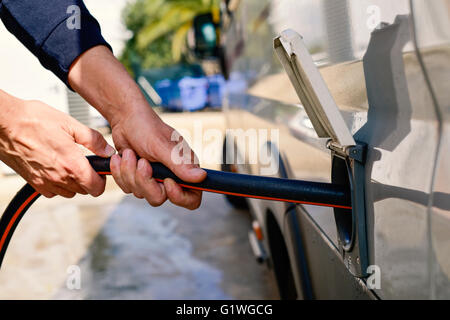 Nahaufnahme eines jungen Mannes Einfüllen des Wassers von einem Campervan einen Schlauch Stockfoto