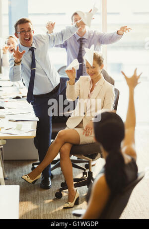 Spielerische Geschäftsleute werfen Papierflieger an einander im Büro Stockfoto