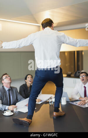 Überrascht Kollegen gerade üppige Geschäftsmann tanzen am Konferenztisch Stockfoto