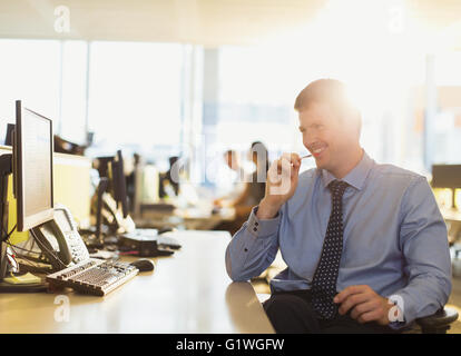 Lächelnde Geschäftsmann am Computer in sonnigen Büro Stockfoto