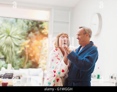 Älteres Paar im Bademantel zu Hause tanzen lachen Stockfoto