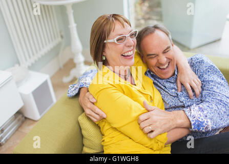 Älteres paar Lachen und umarmt auf sofa Stockfoto