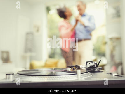 Älteres paar tanzen im Wohnzimmer hinter Plattenspieler Stockfoto