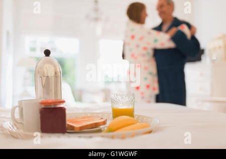 Älteres Paar im Bademantel tanzen hinter Frühstück im Bett Stockfoto