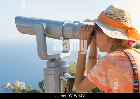 Junge Frau, die durch öffentliche Fernglas am Horizont. Sommerurlaub Stockfoto