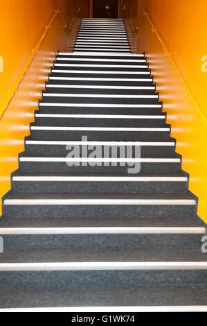 Langen graue Treppen mit vielen Schritten in einem hohen Gebäude mit gelben Wand Stockfoto