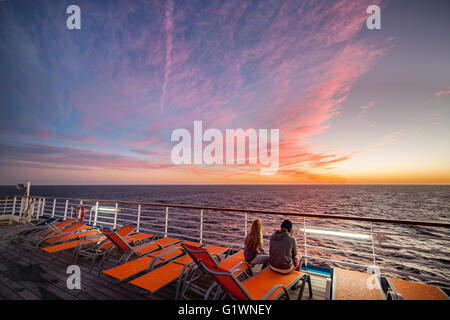 Orangefarbene Liegestühle auf einer Cruse Schiff gegen eine orange farbigen Sonnenuntergang. Stockfoto