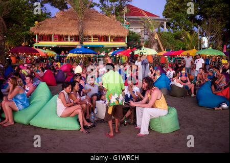 Westliche Urlauber genießen Sie einen Drink am Strand, während die Sonne über der Insel Bali in Indonesien beim trinken Cocktails. eingestellt. Stockfoto