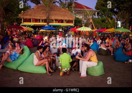 Westliche Urlauber genießen Sie einen Drink am Strand, während die Sonne über der Insel Bali in Indonesien beim trinken Cocktails. eingestellt. Stockfoto