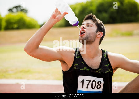 Müde Sportler sitzen auf der Laufstrecke und Trinkwasser Stockfoto