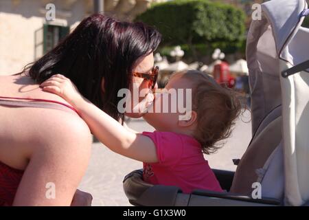 Ein wunderschönes kleines Mädchen küsst ihre Mama Stockfoto