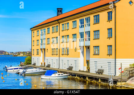 Karlskrona, Schweden - 3. Mai 2016: Coastal Mehrfamilienhaus auf Stumholmen in der Stadt. Gebäude ist gelb. Kleine Sportboote Stockfoto