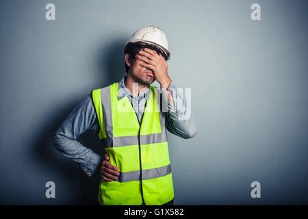 Ein junger Ingenieur tragen eine hohe Vis und Schutzhelm ist sein Gesicht abdecken. Stockfoto