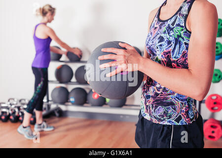 Eine junge Frau steht in der Turnhalle und hält einen Medizinball Stockfoto