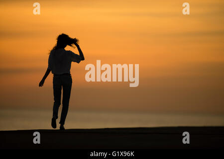 Eine Silhouette junge attraktive schlanke Brünette Frau Mädchen Wandern bei Sonnenuntergang im freien außerhalb an einem warmen Abend. UK Stockfoto