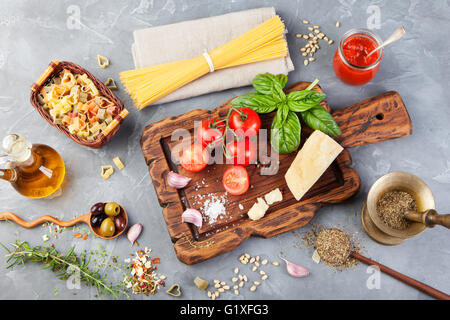 Italienisches Essen Hintergrund mit Strauchtomaten, Basilikum, Spaghetti, Oliven, Parmesan, Olivenöl, Knoblauch Stockfoto