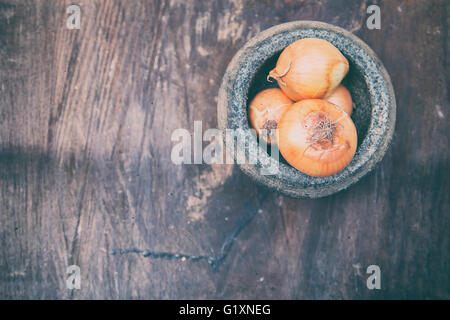 Soft Image der Zwiebeln und Steinmörser auf alte hölzerne. Stockfoto