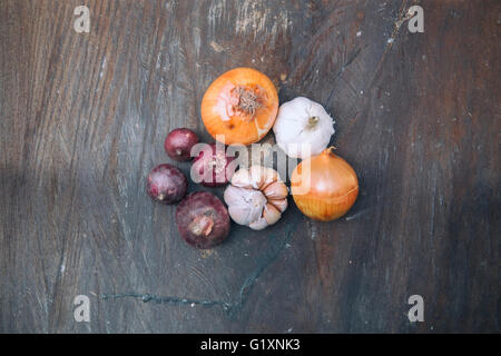 Weiches Bild der roten Zwiebeln, Zwiebeln, Knoblauch und Steinmörser auf alte hölzerne. Selektiven Fokus mit geringen Schärfentiefe. Stockfoto