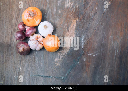 Weiches Bild der roten Zwiebeln, Zwiebeln, Knoblauch und Steinmörser auf alte hölzerne. Selektiven Fokus mit geringen Schärfentiefe. Stockfoto