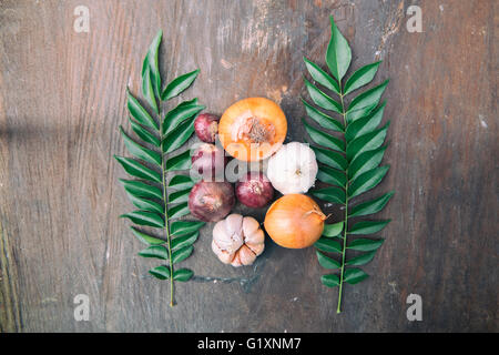 Weiches Bild von roten Zwiebeln, Knoblauch, Schalotten und Curry Blätter oben auf alten Holz in natürlichem Licht. Stockfoto