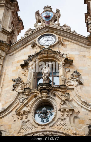 Frontansicht der Basilika/Iglesia de Santa Maria del Coro, San Sebastian, Spanien, zeigt die verzierten religiösen Schnitzereien und Statuen und Uhren Stockfoto