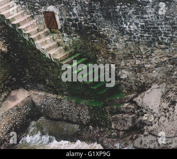 Betontreppen gegen eine Steinmauer auf Meereshöhe leading Stockfoto