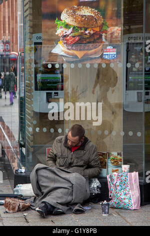 Eine Obdachlose rough sleeper Mann in den Bürgersteig in schlechtem Zustand sitzt in Liverpool, Merseyside, UK Stockfoto