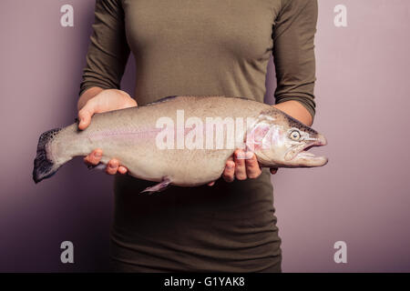 Eine junge Frau hält eine Regenbogenforelle Stockfoto