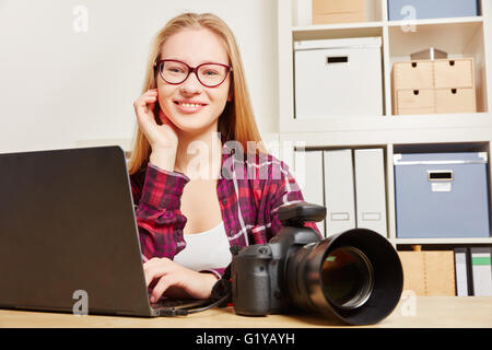Frau als Fotograf mit Laptop und DSLR-Kamera, die sitzen in ihrem Büro Stockfoto