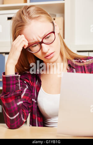 Frau mit einem Burnout sieht besorgt auf Rechnung auf ihre Hand in ihr Büro Stockfoto