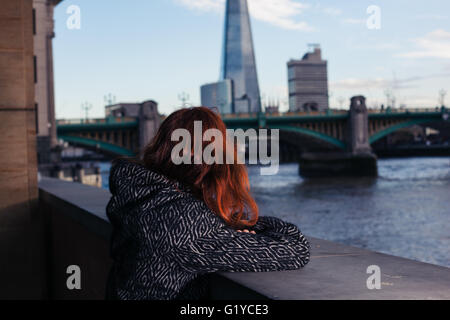 Eine junge Frau blickt auf den Fluss Themse in London Stockfoto