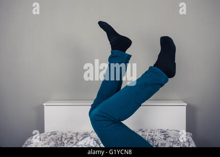 Ein Mann liegt im Bett mit seiner Beine angehoben Stockfoto