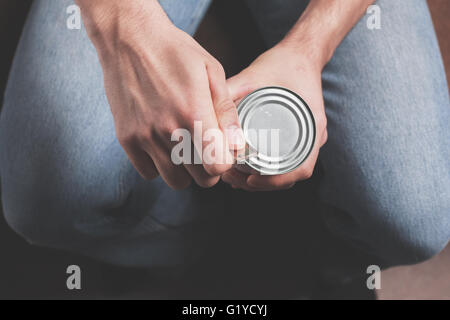 Ein Mann ist eine Dose mit einem Dosenöffner öffnen. Stockfoto