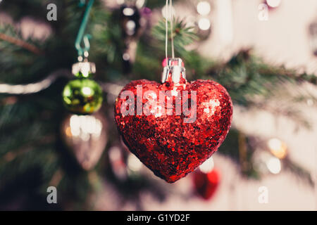Ein dekoratives rotes Herz hängend von einem Weihnachtsbaum Stockfoto
