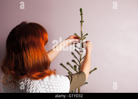 Eine junge Frau ist ein Weihnachtsbaum schmücken. Stockfoto