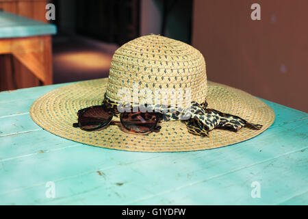 Stroh Hut und eine Sonnenbrille auf einem Tisch in der Sonne Stockfoto