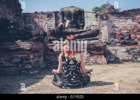 Eine junge Frau sitzt und den Ruinen eines antiken buddhistischen Tempels meditieren Stockfoto