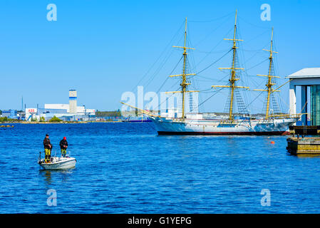 Karlskrona, Schweden - 5. Mai 2016: Drei junge Erwachsene Männer Stand in einen Halbmond Motorboot Angeln mit Rute und anzugehen. Alten Segeln s Stockfoto