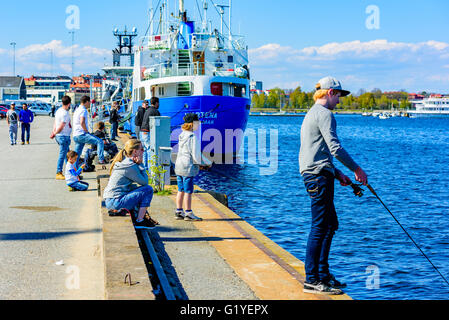 Karlskrona, Schweden - 5. Mai 2016: Echte Menschen im Alltag. Menschen stehen entlang dem Hafen Pier Fischerei nach Hering mit ro Stockfoto