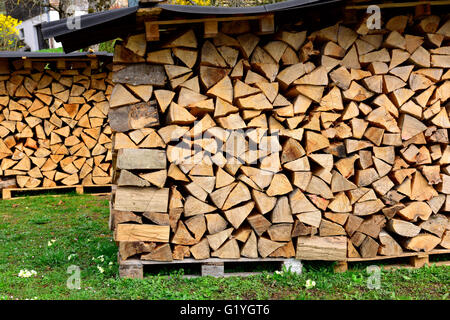 Stapel von Protokollen für Brennholz unter Blechdach würzen Stockfoto