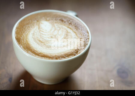 frische heiße Tasse Kaffee Latte Kunst auf Holztisch Stockfoto