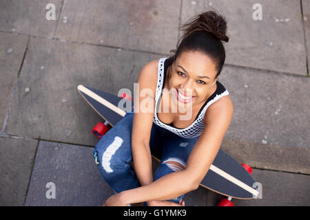 junge Frau sitzt auf ihrem skateboard Stockfoto