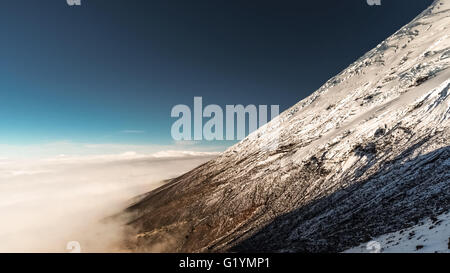 Berg, teilweise mit Schnee bedeckt schwebt über den Wolken. Stockfoto