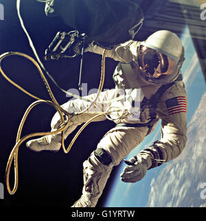 NASA-Astronaut Ed White schwebt in der Schwerelosigkeit der Raum außerhalb der Gemini 4-Sonde mit dem Blau der Erde unten während der ersten Weltraumspaziergang durch eine amerikanische 3. Juni 1965 in der Erdumlaufbahn. Weiß um die Sonde durch eine Nabelschnur Linie 25 Fuß und eine Linie 23-ft Leine befestigt war, beide in gold Band bilden eine Schnur gewickelt. In seiner rechten Hand trägt weiß eine Hand Held selbst manövrieren Einheit, die verwendet wird, um sich in der Schwerelosigkeit des Weltraums bewegen. Stockfoto