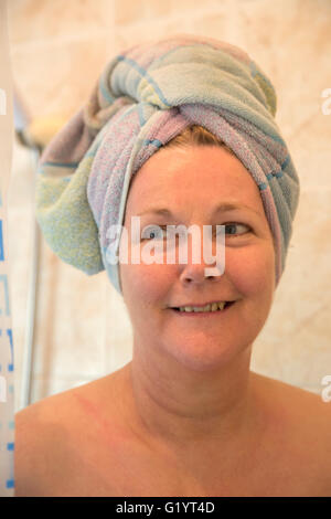 50 Jahre alte Frau in der Dusche mit Handtuch auf Kopf. Stockfoto
