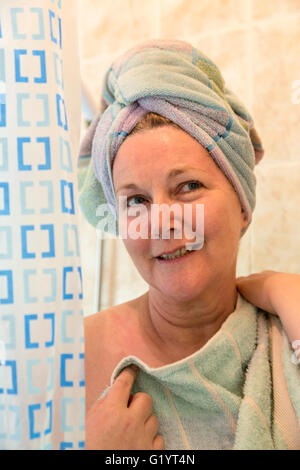 50 Jahre alte Frau in der Dusche mit Handtuch auf Kopf. Stockfoto
