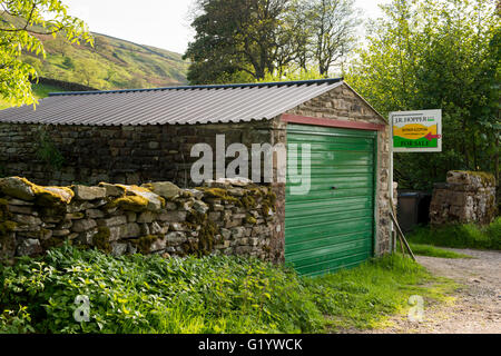 Haus zum Verkauf in einer wunderschönen Landschaft in der Nähe von Muker Village, North Yorkshire, England - Estate Agent Zeichen in Garage befestigt. Stockfoto