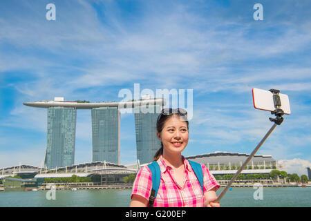 Lächelnde junge Frau machen Selfie in der Nähe von Marina Bay Sands Hotel, Singapur Stockfoto