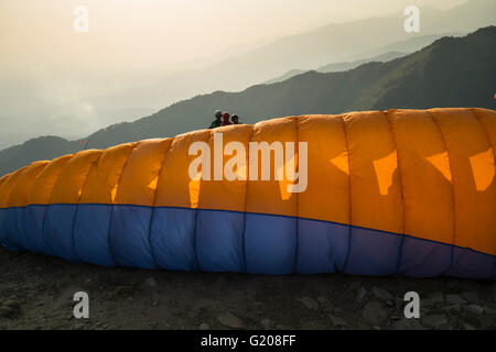 Ein Gleitschirm steigt mit dem Wind in den Flügeln gegen die untergehende Sonne in Bir Abrechnung, Himachal Pradesh Stockfoto